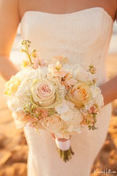 a bride holding a bouquet of flowers in her hand on the beach at sunset or sunrise