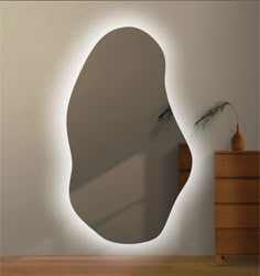 a mirror that is on the wall in front of a dresser and vase next to it