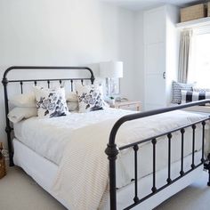 a bedroom with a white bed and black iron frame headboard, lamps on either side of the bed