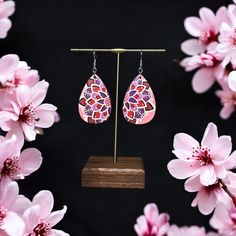 These bright and fun earrings feature a hand-painted mandala in shades of pink, purple, and maroon. Perfect for adding a vibrant touch of art to your look, they are ideal for when you want to make a bold statement. Earrings are hand painted on teardrop shaped , lightweight wood (2x1.5in.), and sealed with a non-toxic satin finish. The earring hooks are hypoallergenic stainless steel. Pink Teardrop Festival Earrings, Purple Hand Painted Bohemian Earrings, Pink Teardrop Earrings For Festival, Pink Teardrop Jewelry For Festivals, Bohemian Hand Painted Purple Earrings, Bohemian Pink Teardrop Dangle Earrings, Handmade Pink Bohemian Teardrop Earrings, Bohemian Pink Hand Painted Earrings, Pink Bohemian Hand Painted Jewelry