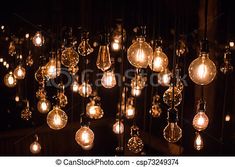 an array of light bulbs hanging from the ceiling in a dark room with black walls