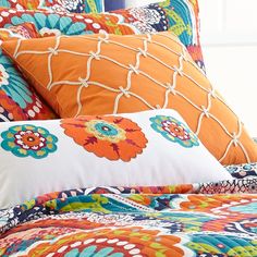 an orange and blue bed with colorful pillows