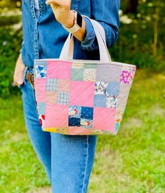 a woman carrying a pink and blue patchwork tote bag on her left hand