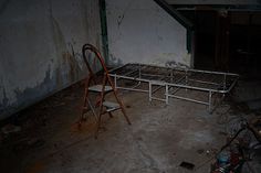 an old bed frame sitting in the middle of a room with peeling paint on it