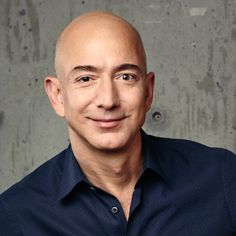 a balding man with his hands on his hips posing for a photo in front of a concrete wall