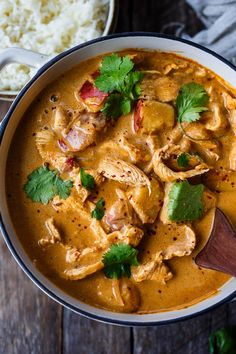 a bowl filled with chicken curry and garnished with cilantro