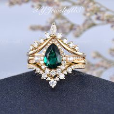 a close up view of a ring with a green stone and white pearls on it