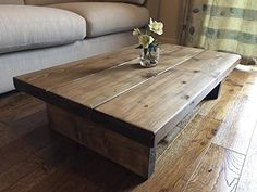 a wooden coffee table with flowers in a vase on the top, and a couch behind it