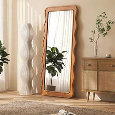 a mirror sitting on top of a wooden floor next to a plant in a vase