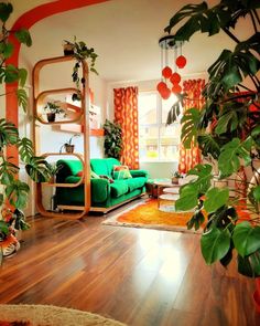 a living room filled with green furniture and lots of plants on top of wooden floors