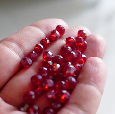 a person holding some red beads in their hand