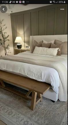 a large bed sitting next to a night stand on top of a wooden table in a bedroom