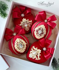 red and gold ornaments in a white box with ribbon around the edges, on display