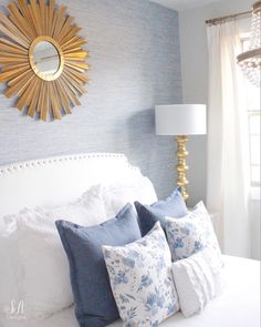 a white bed topped with pillows and a gold sunburst above the headboard