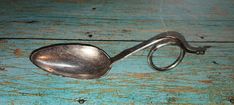 a metal spoon sitting on top of a blue wooden table next to a pair of scissors