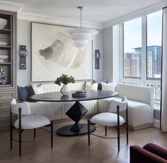 a dining room table with white chairs and a large painting on the wall behind it