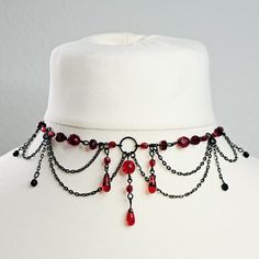 a white mannequin with black chains and red beads on it's neck