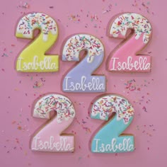 the numbers are decorated with icing and sprinkles on a pink background