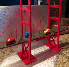 two toy cars are driving across the bridge