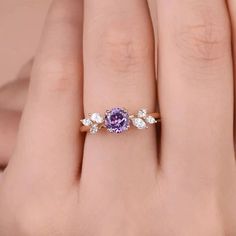 a woman's hand with a ring on it and a purple stone in the middle