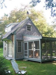 a small gray house sitting on top of a lush green field