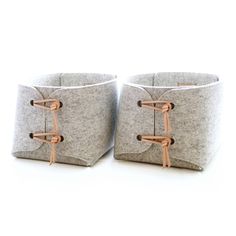 two gray baskets with handles on each side, one is made out of felt and the other has copper wire