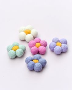 four different colored felt flowers on a white surface