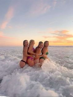 four women in bikinis are sitting on the back of a boat at sunset or dawn