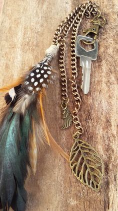 a feather, key and chain on a piece of wood