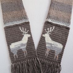 a knit scarf with an image of a deer on the front, and fringe around the neck