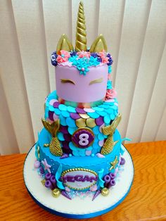 a three tiered cake decorated with an unicorn's head and numbers on it