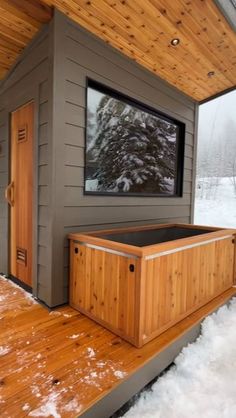 an outdoor sauna in the snow with wood flooring and wooden doors on it