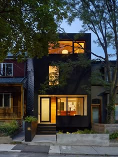 a black house with lots of windows on the front and side of it at night