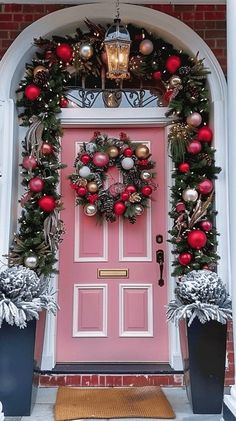 a pink front door decorated with christmas decorations