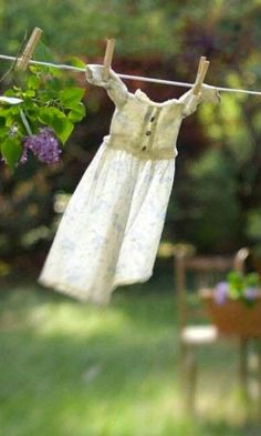 clothes hanging out to dry on a clothes line in the yard with purple flowers and greenery