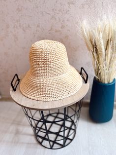 a straw hat sitting on top of a table next to a vase with dry grass