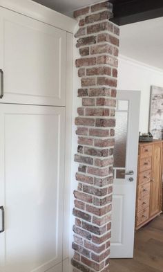 a tall brick pillar in the middle of a room with white cupboards and drawers