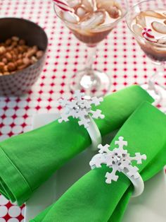 two napkins with snowflakes on them sitting on a table next to glasses