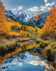 the mountains are covered in autumn foliage and trees with yellow leaves on them, as well as some water