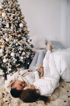 a woman laying on the floor in front of a christmas tree