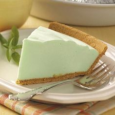 a piece of pie on a plate with a fork and bowl in the back ground