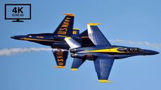 two blue and yellow fighter jets flying in the sky