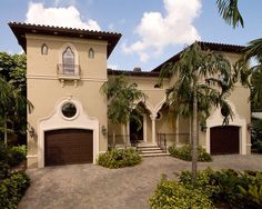 a house with palm trees in front of it and two garages on the other side