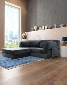 a living room with hardwood floors and a gray couch in front of a large window