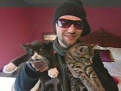 a man holding two cats in his arms while wearing sunglasses and a knitted hat