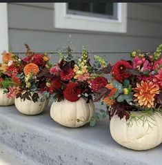 four white pumpkin vases filled with colorful flowers