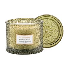 a candle that is sitting on top of a white surface with an ornate design in the middle