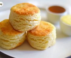 three biscuits stacked on top of each other on a plate with dipping sauces in the background