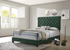 a bed with green headboard and foot board in a white room next to a window