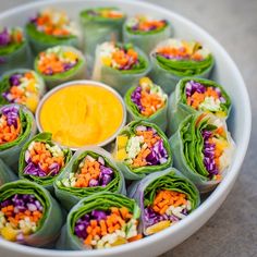 there are many rolls with different colored vegetables in them and a dipping sauce on top